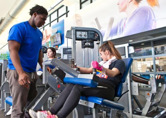 Girl receiving instruction on leg machine